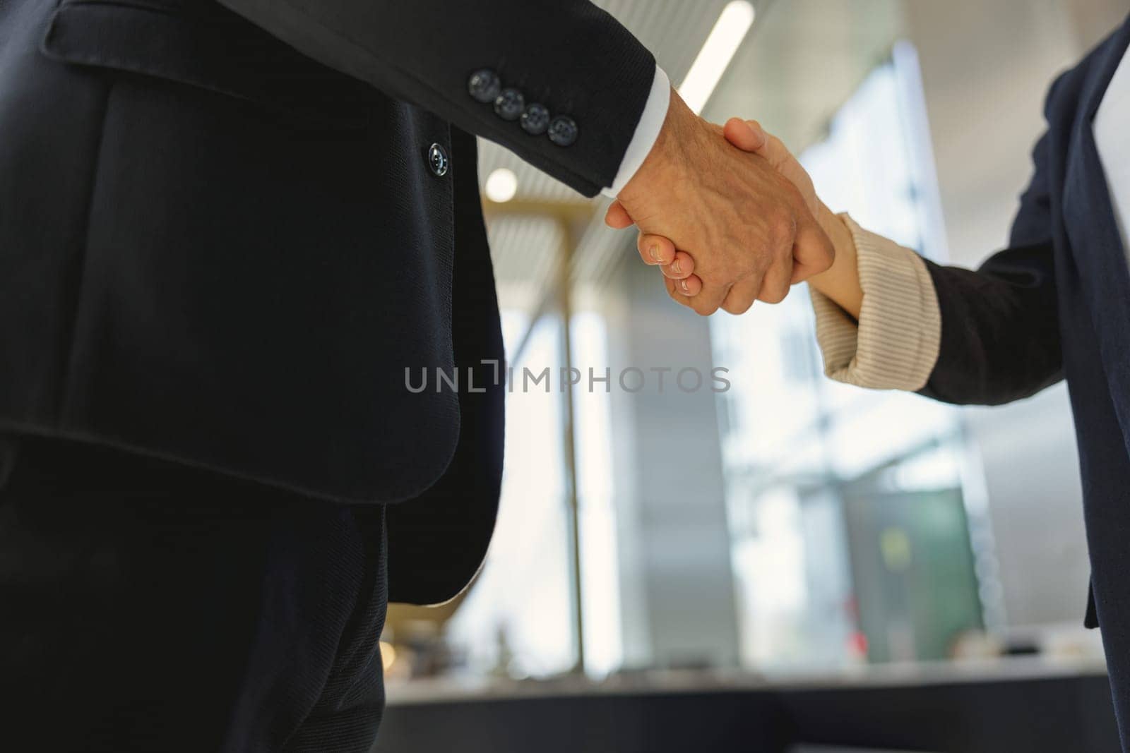 Business partners shaking hands in front of the modern office background. High quality photo
