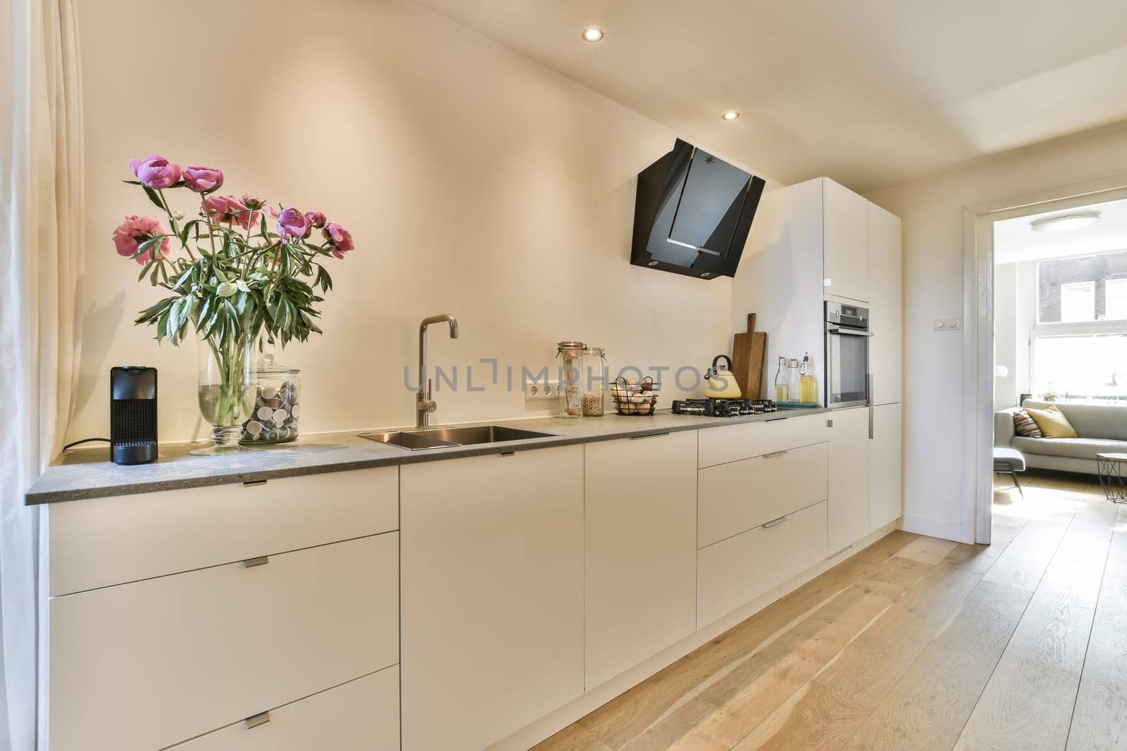 a kitchen with flowers on the counter and tv mounted to the wall in the living room next to the dining area