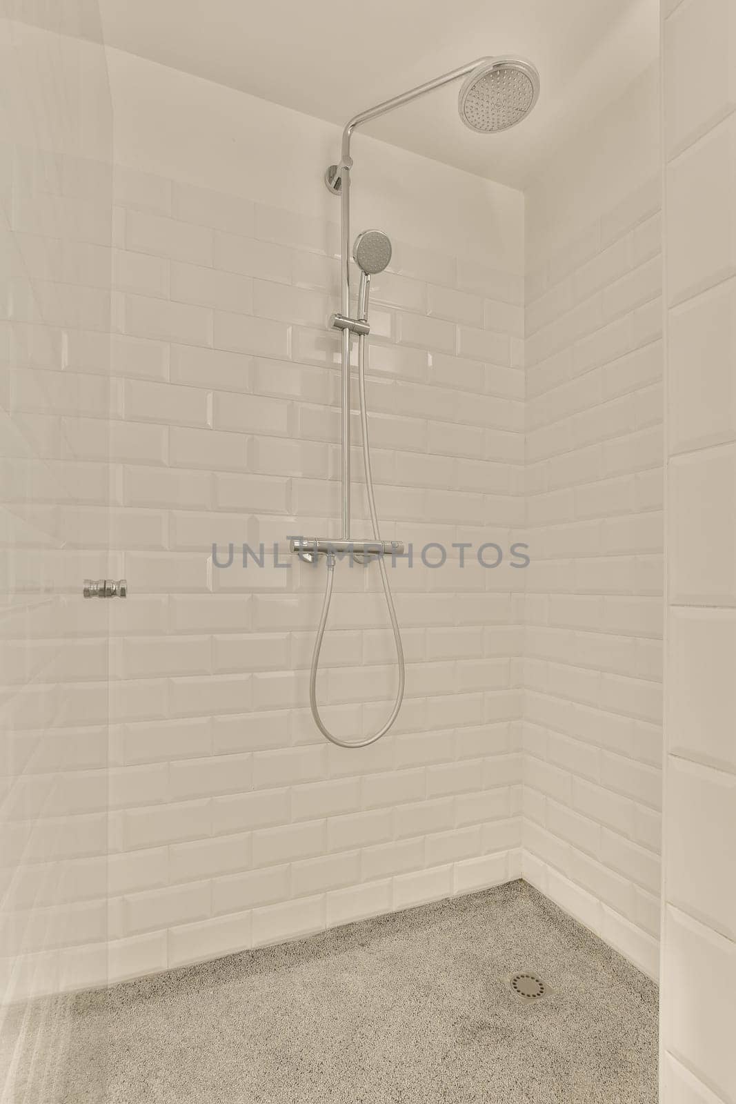 a white tiled shower in a bathroom with a by casamedia
