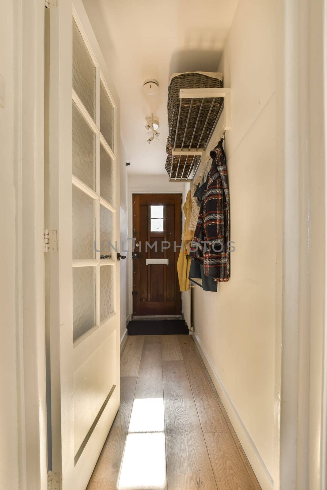 a hallway with white walls and a door and clothes by casamedia