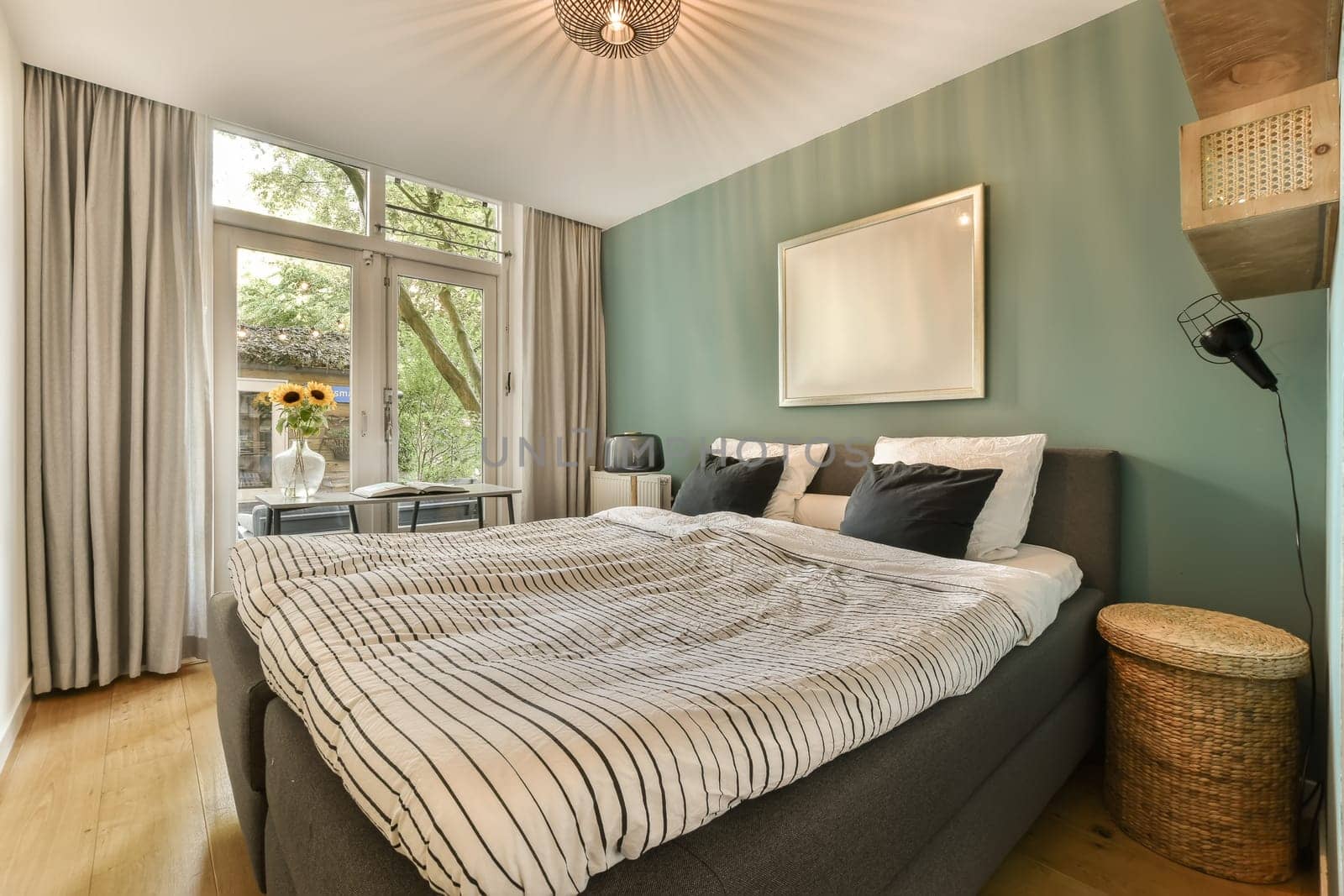 a bedroom with green walls and wood flooring the room has a large bed in it is surrounded by two windows