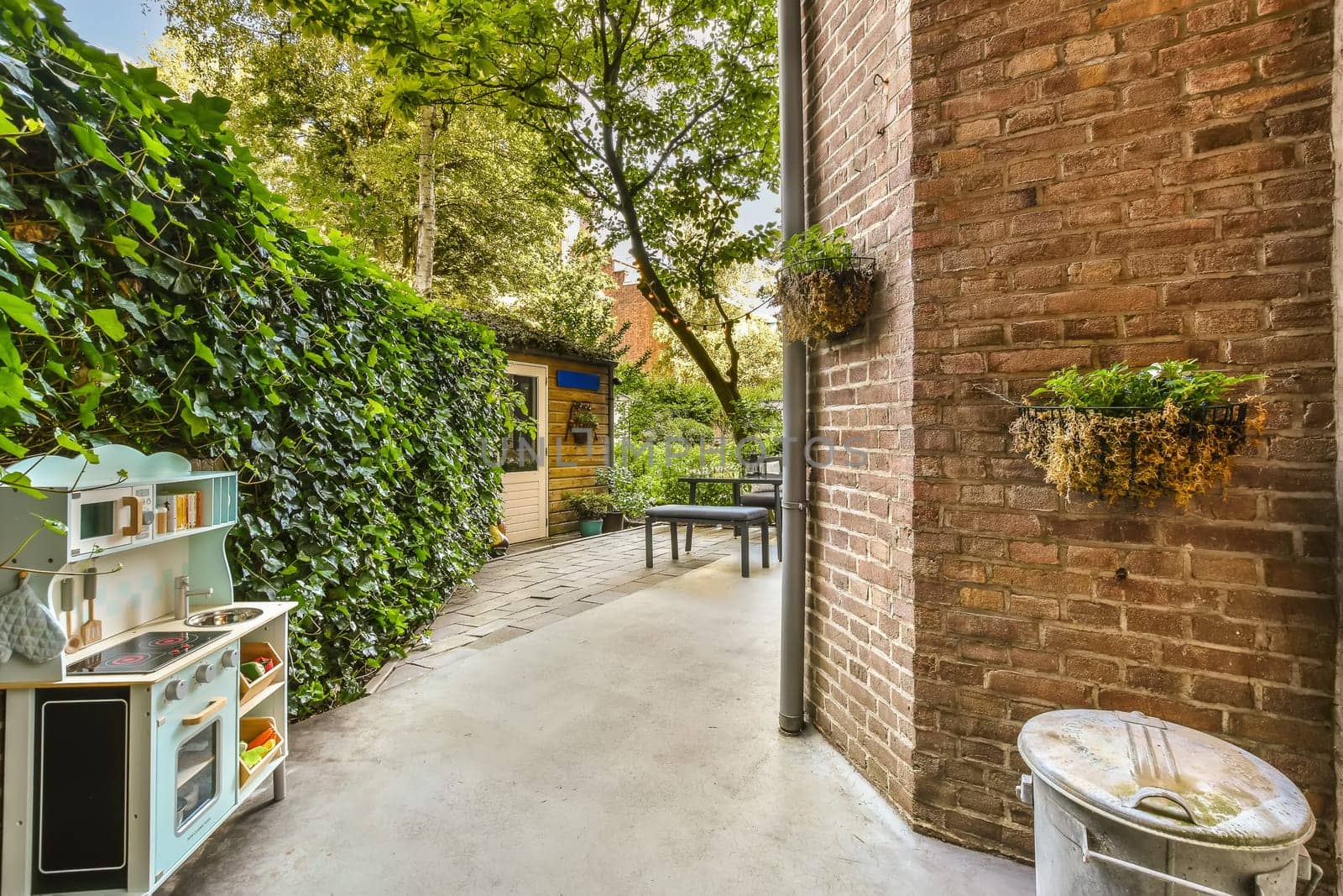 a patio with a brick wall and a garbage can by casamedia