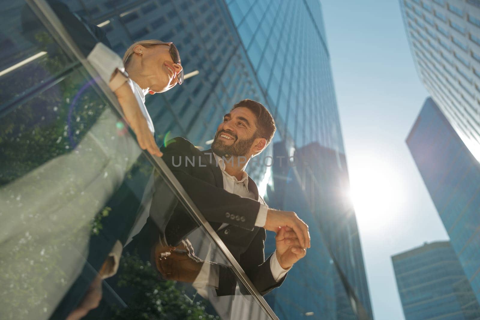 Two colleagues is talking during break time standing on background of modern city skyscrapers by Yaroslav_astakhov