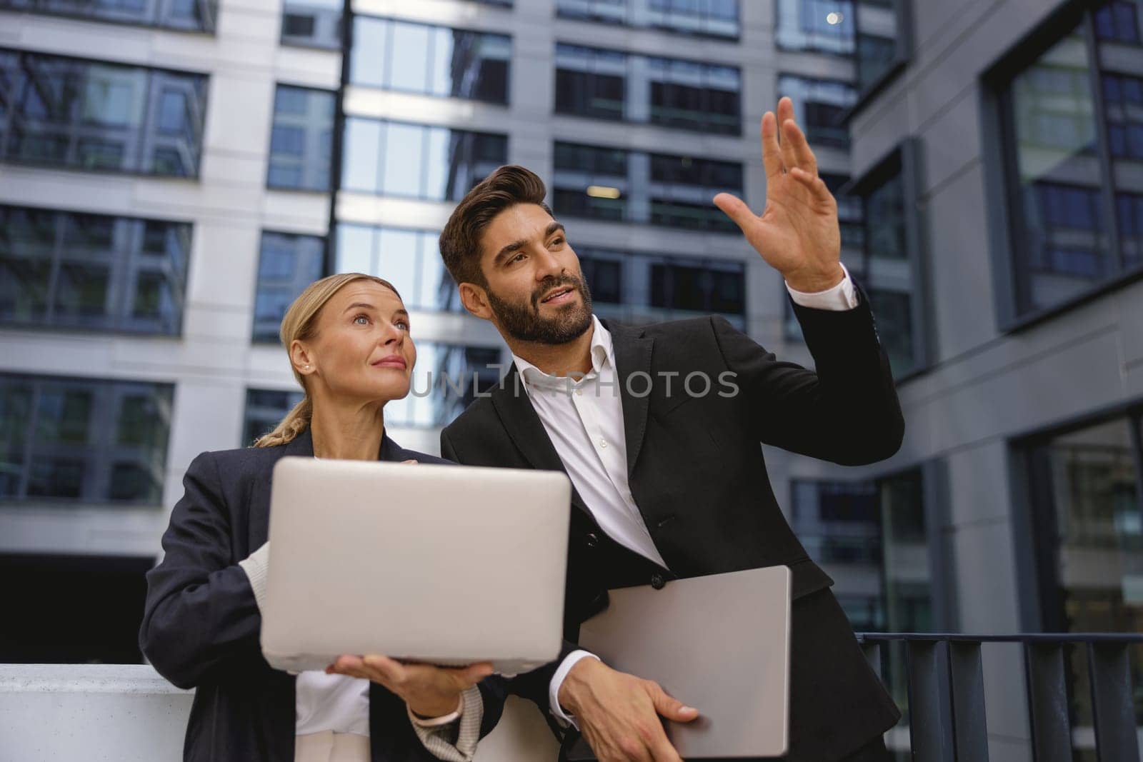Two business colleagues working on project while sitting outdoors on skyscrapers background