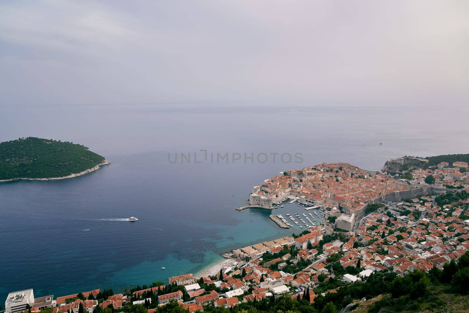 View from the mountain to the yacht sailing on the sea to the port of Dubrovnik. Croatia by Nadtochiy
