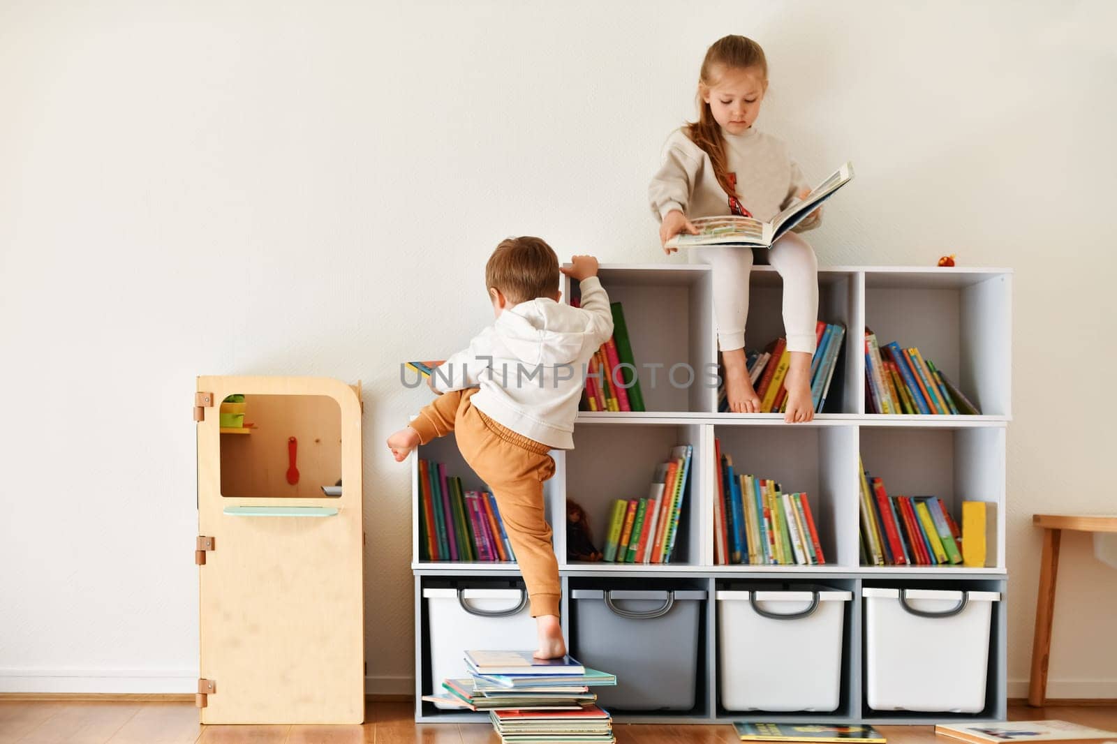 Brother and sister reading books in the white children's room