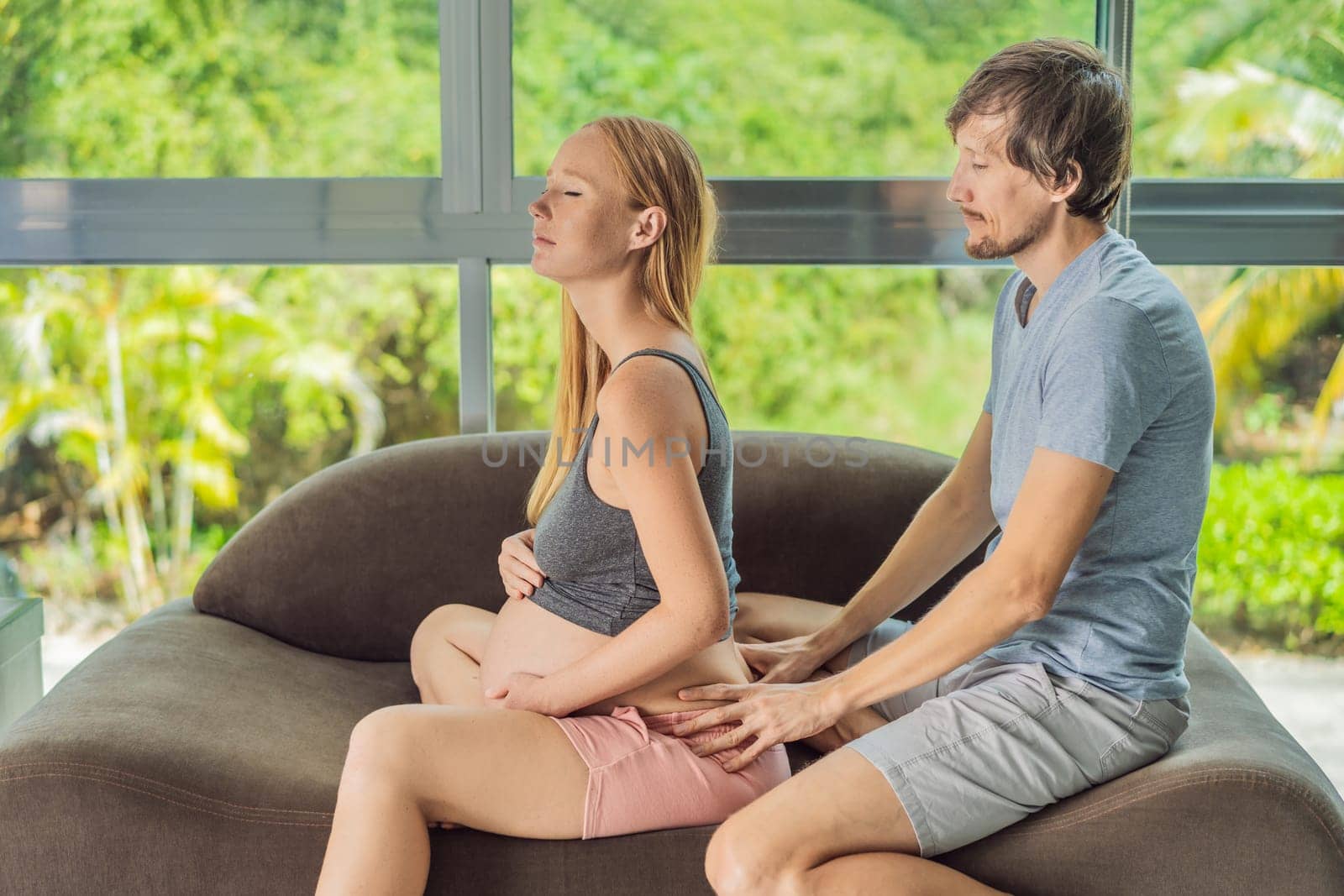 health, pregnancy and happy people concept - husband giving his wife back massage at home by galitskaya