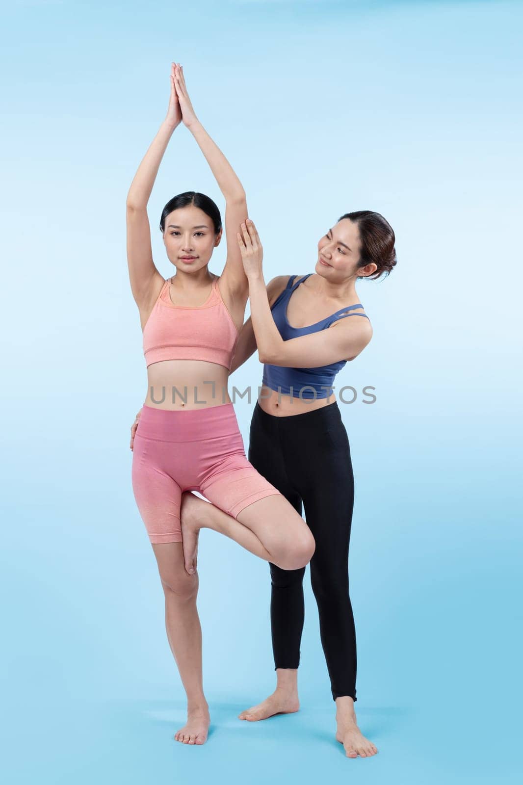 Asian woman in sportswear doing yoga exercise posing with trainer. Vigorous by biancoblue