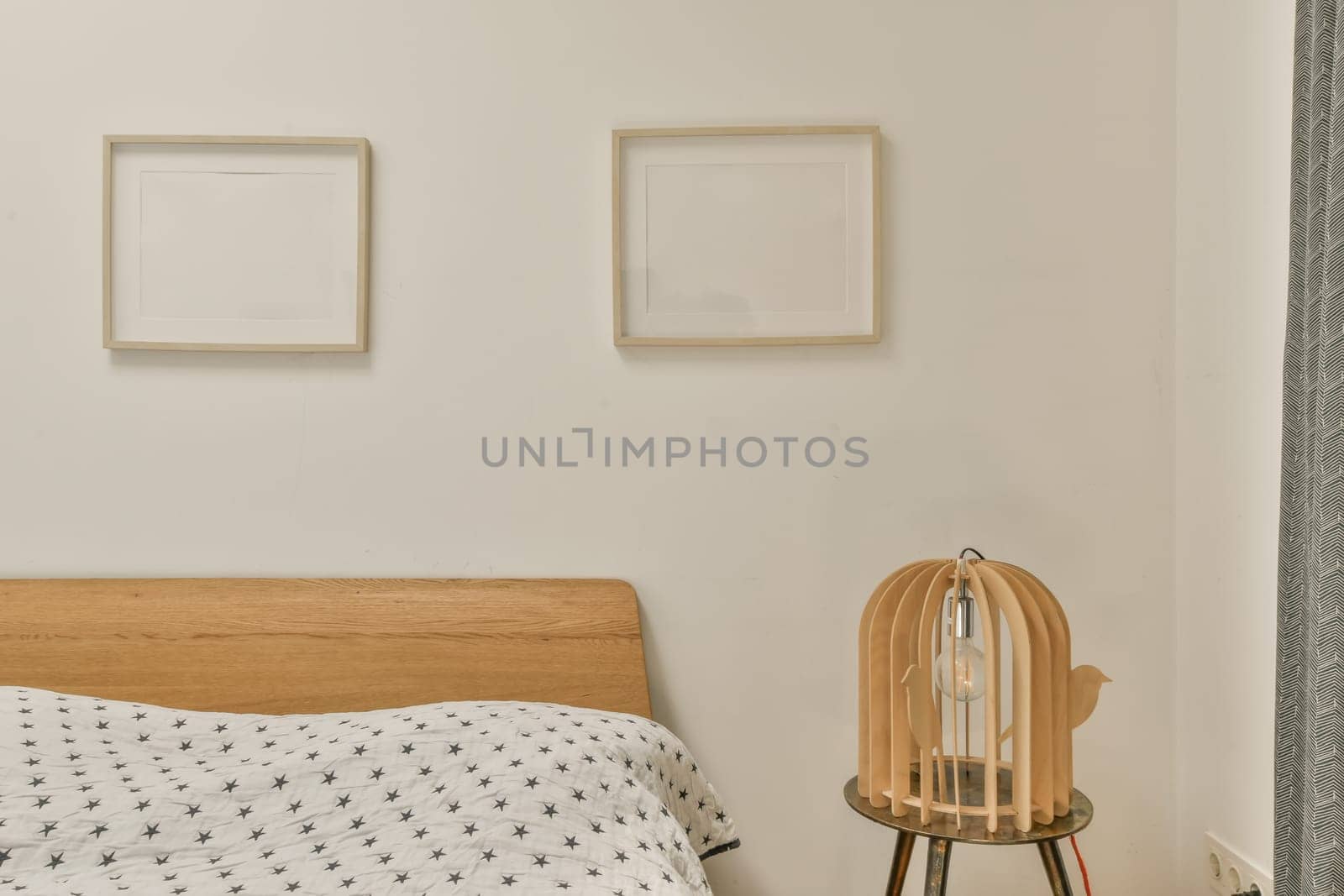 two framed pictures hanging on the wall above a bed in a white bedroom with black and grey patterned bedsprem