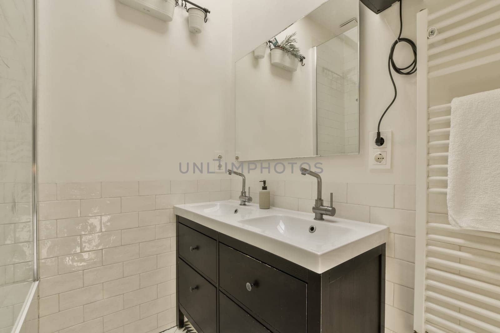 a bathroom with black cabinets and white tiles on the walls, along with a large mirror in the shower stall