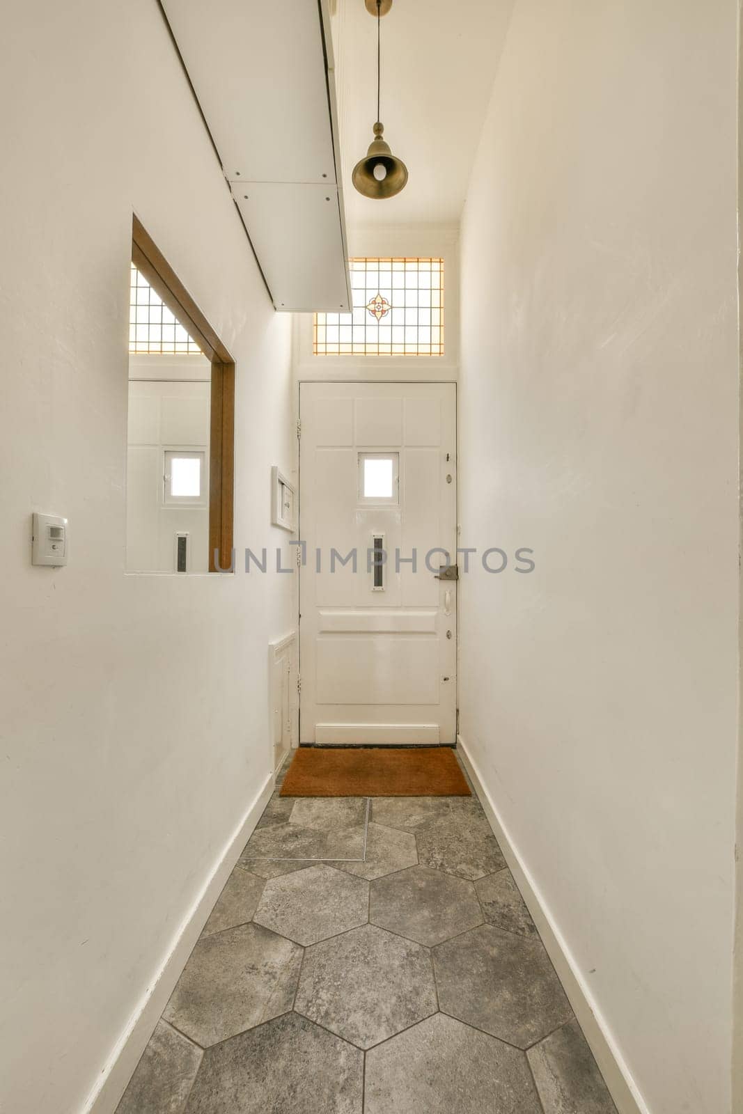 a hallway in a house with white walls and wood trim on the door, light fixture hanging over the doorway