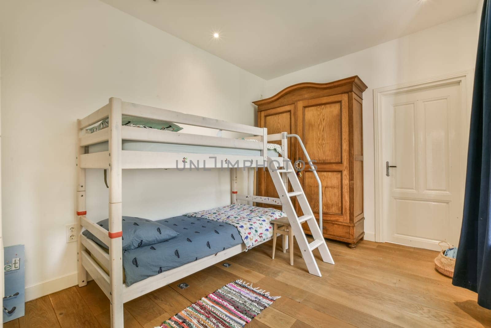 two bunk beds in a bedroom with a wardrobe by casamedia