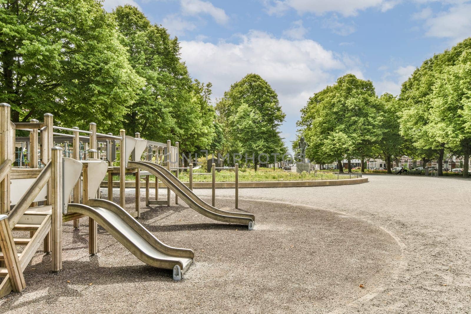 an empty playground in the middle of a park with lots of trees and children's play equipment on it