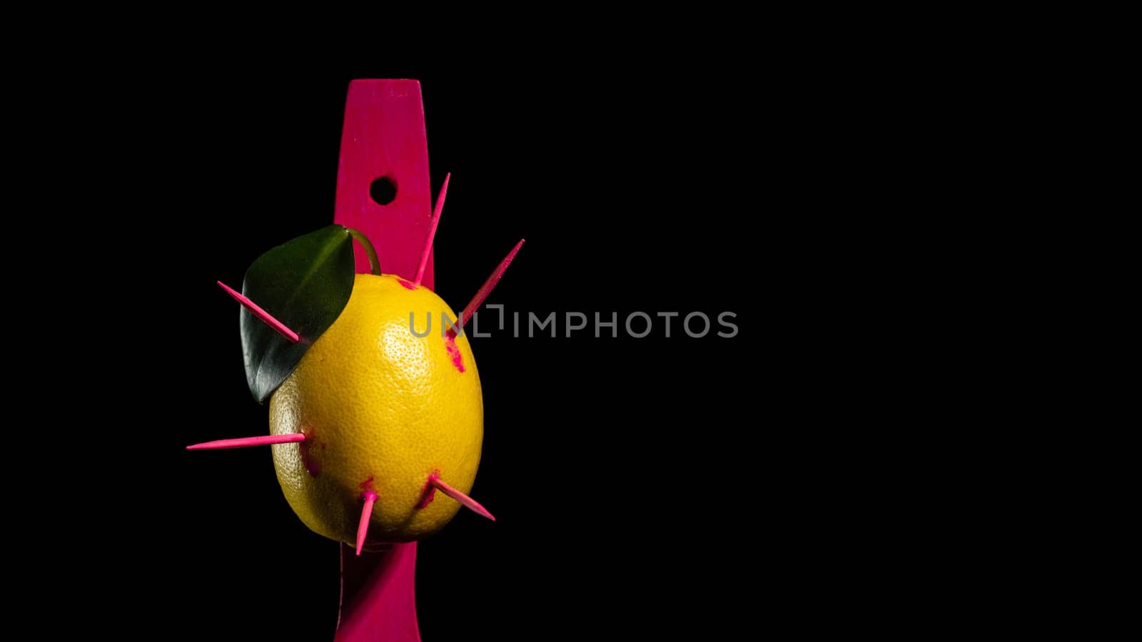 Creative still life with lemon struck by arrows on a black background