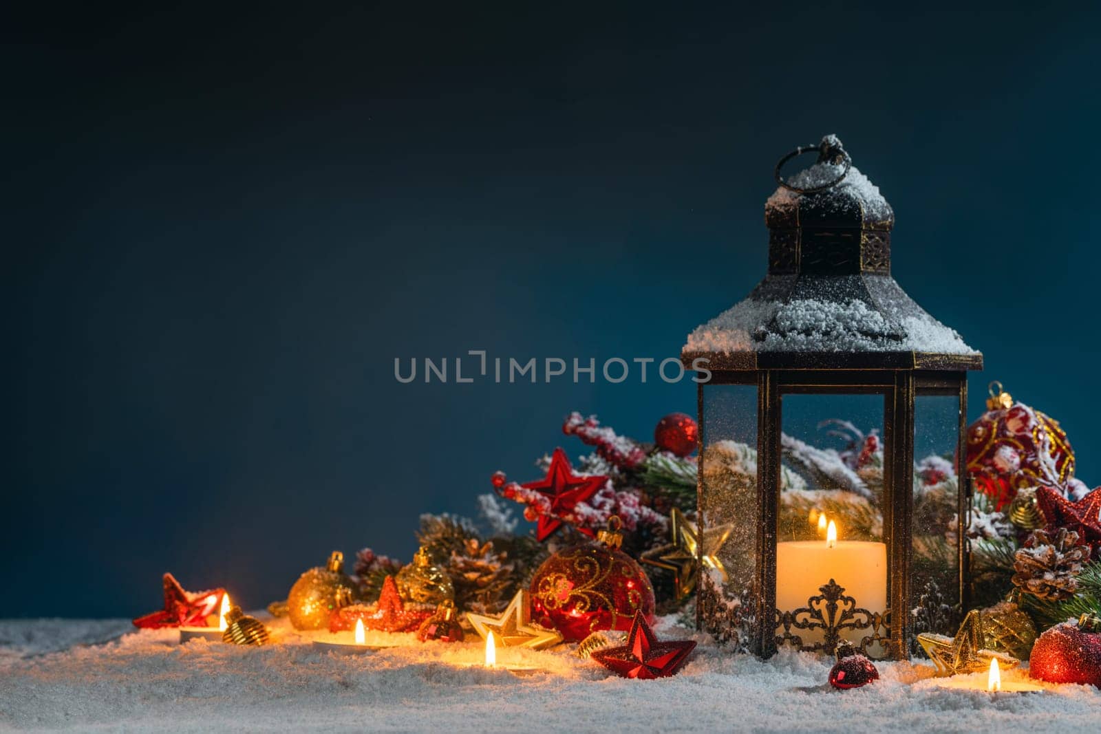 Glowing Christmas lantern and decor of fir tree branches and baubles in snow