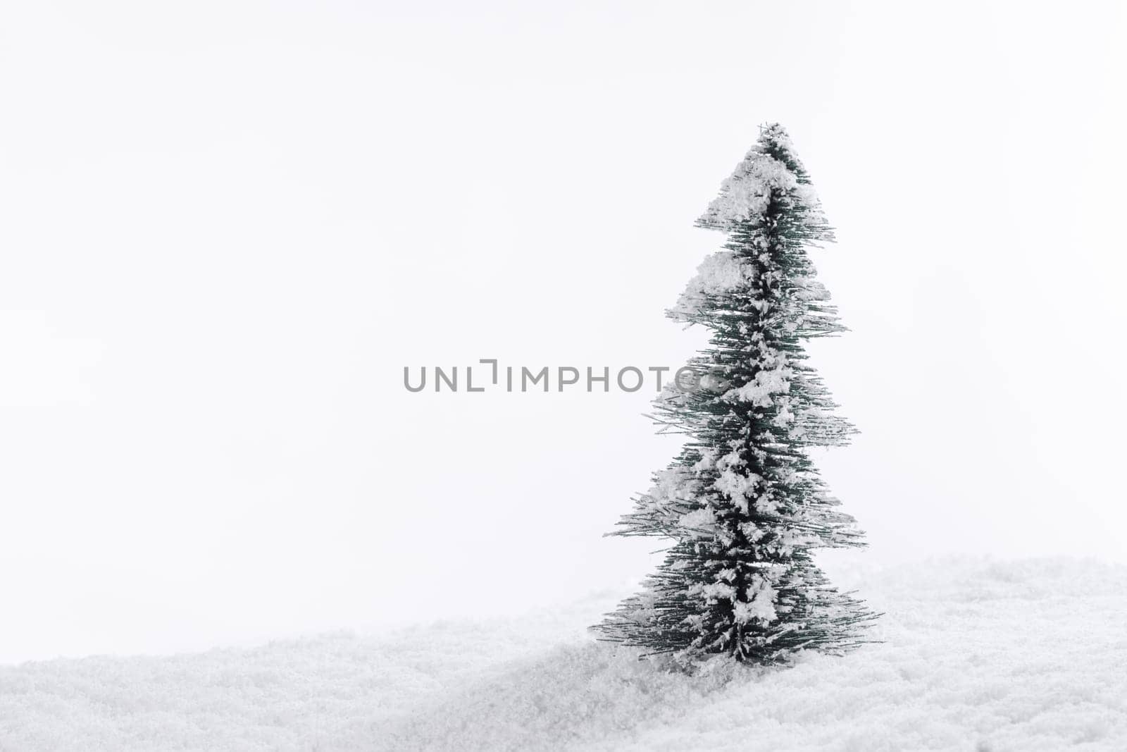Miniature decorative Christmas tree placed on snow isolated on white