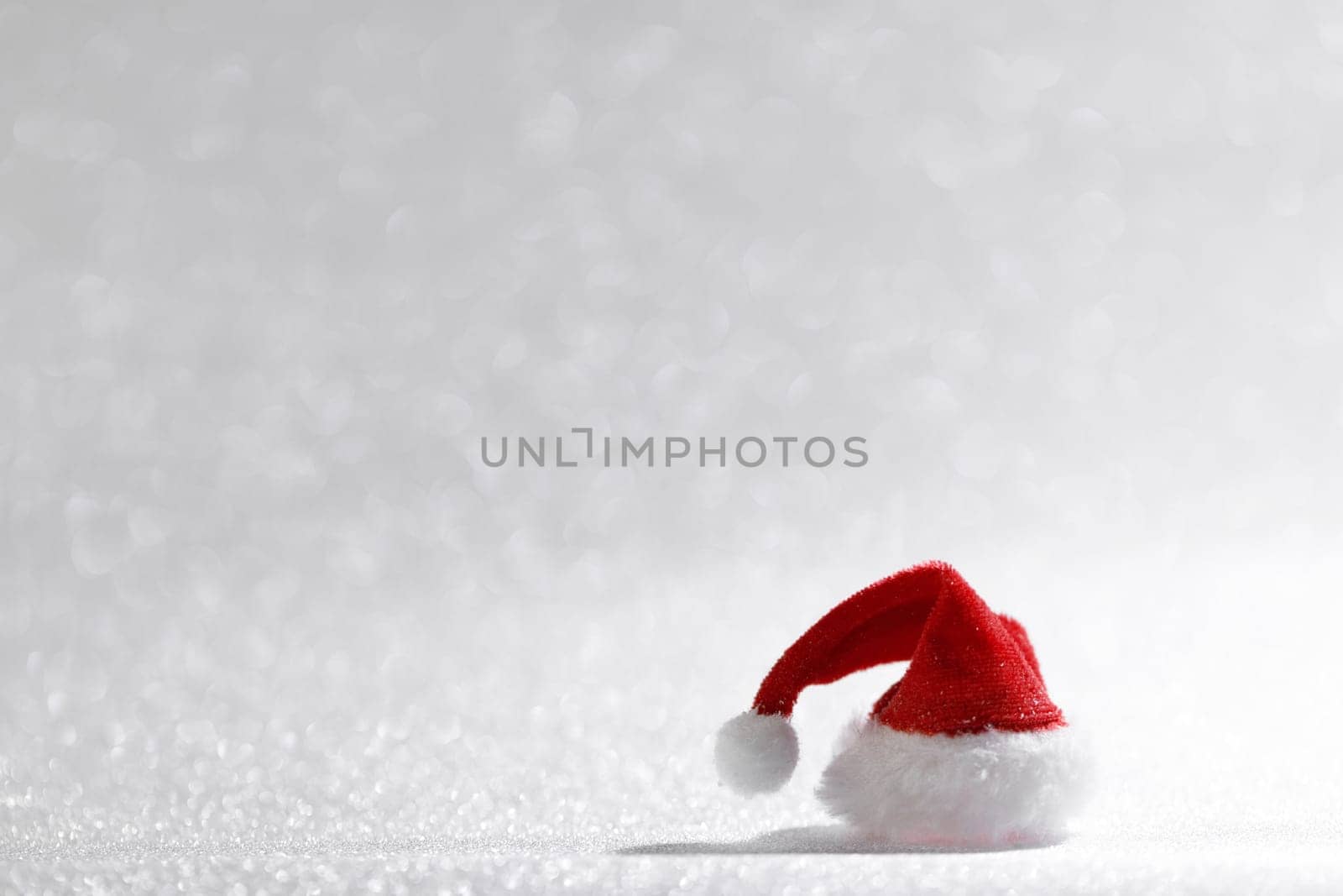 Santa Claus Christmas toy hat on silver glitter background with copy space for text