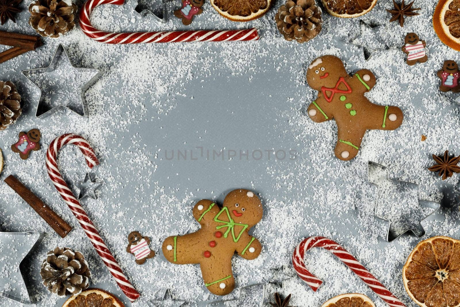 Christmas food gingerbread cookie caramel candy cane cinnamon mold shape anise orange slice on blue background with copy space