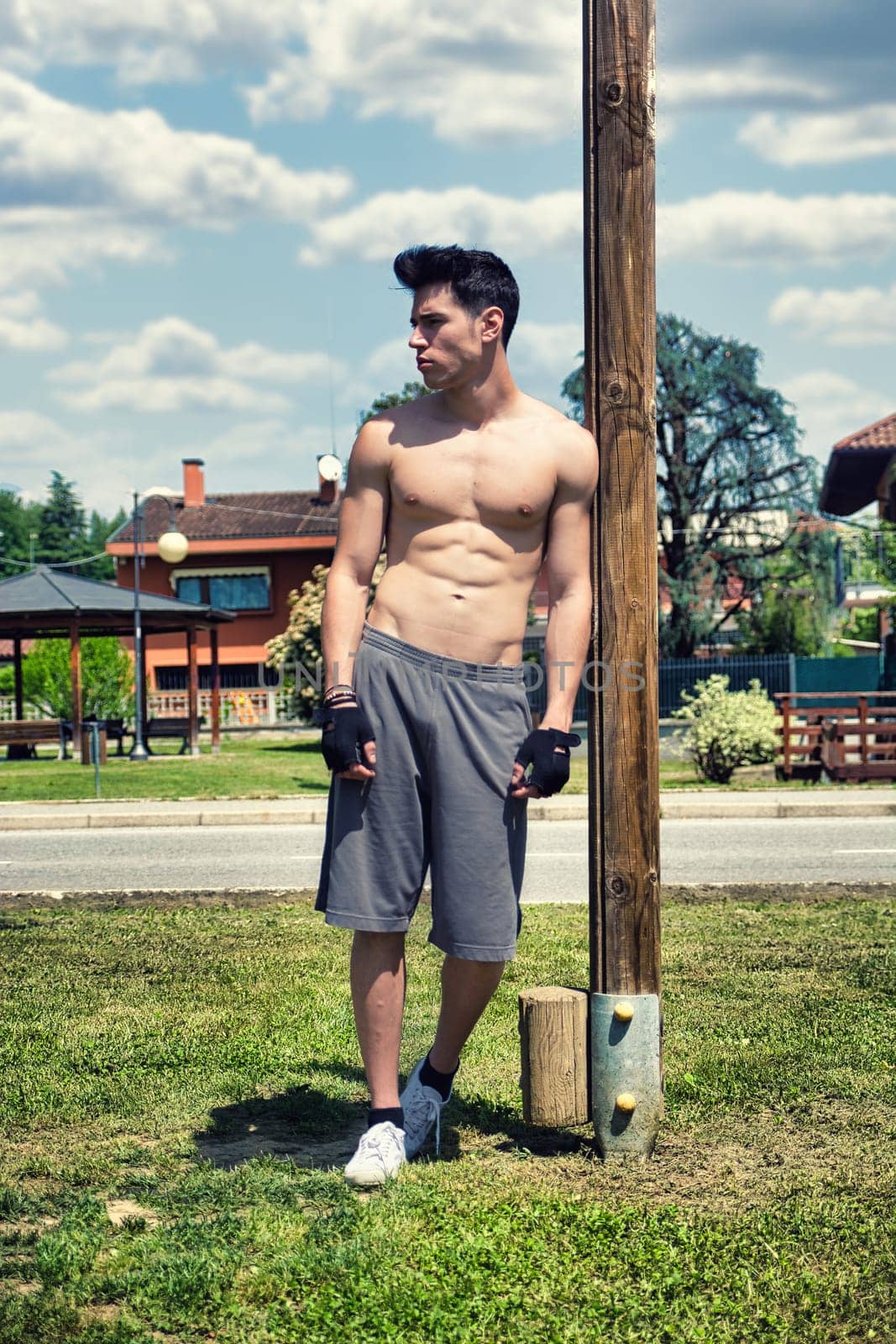 Photo of a shirtless man standing beside a pole by artofphoto
