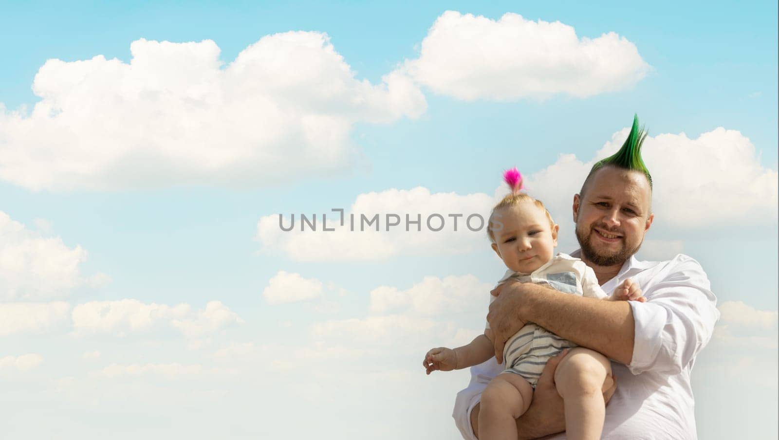 Happy father on vacation - man holding his little baby son on sky background. Portrait