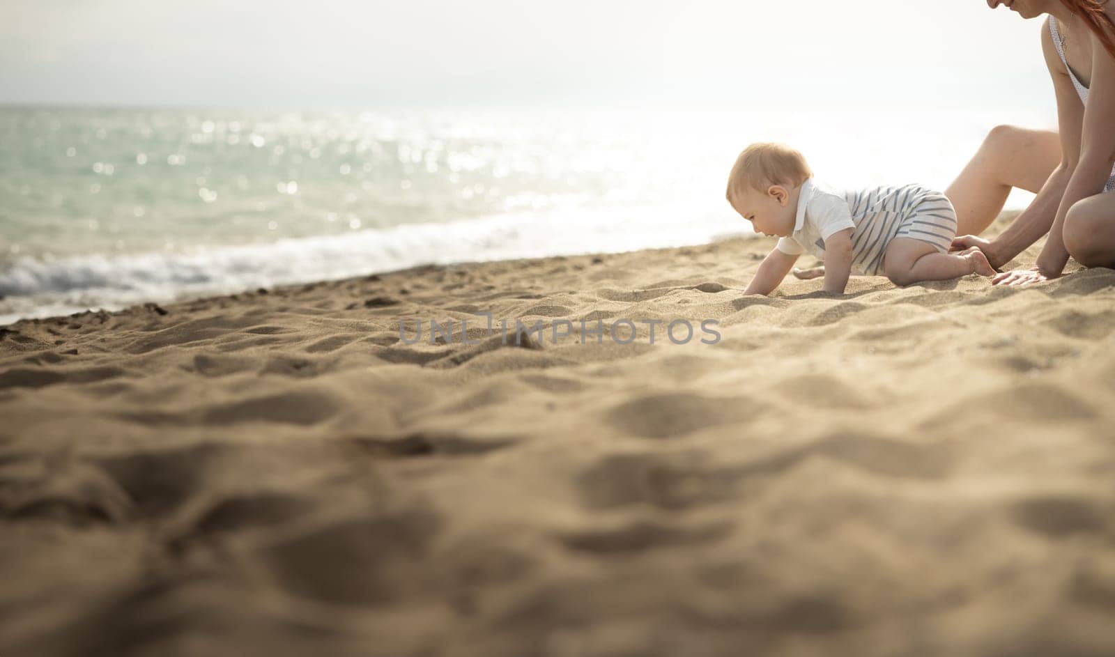 A little baby boy crawling on a sand on the seaside by Studia72