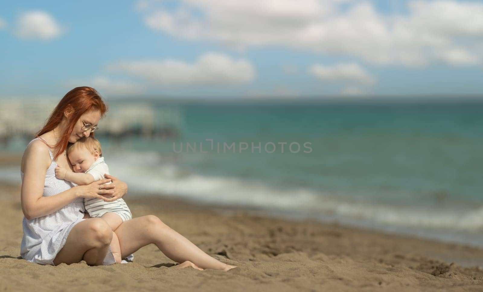 Happy mother and her little son resting on the seaside - hugging. Mid shot