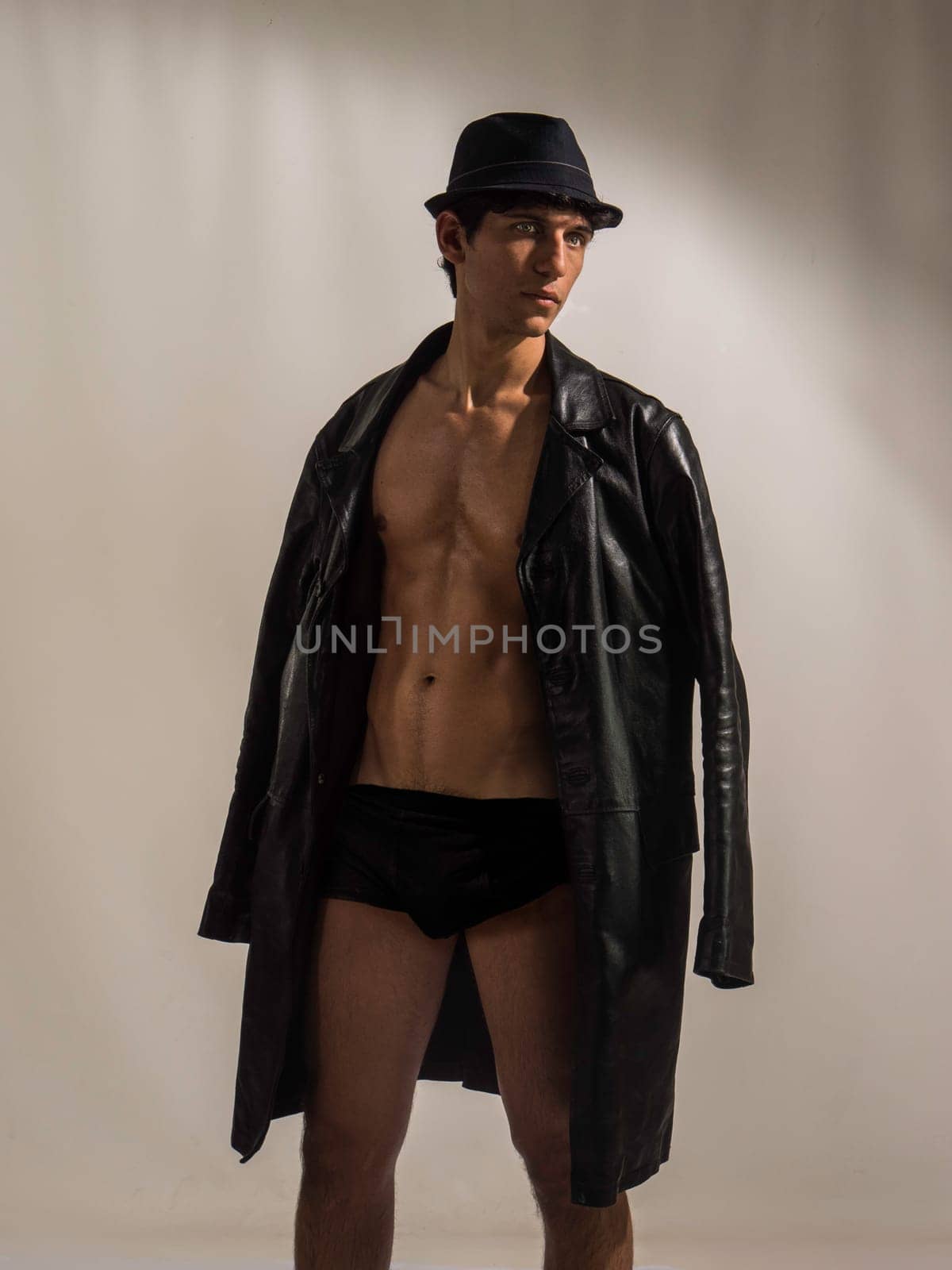 Athletic handsome shirtless young man with leather jacket and fedora hat by artofphoto