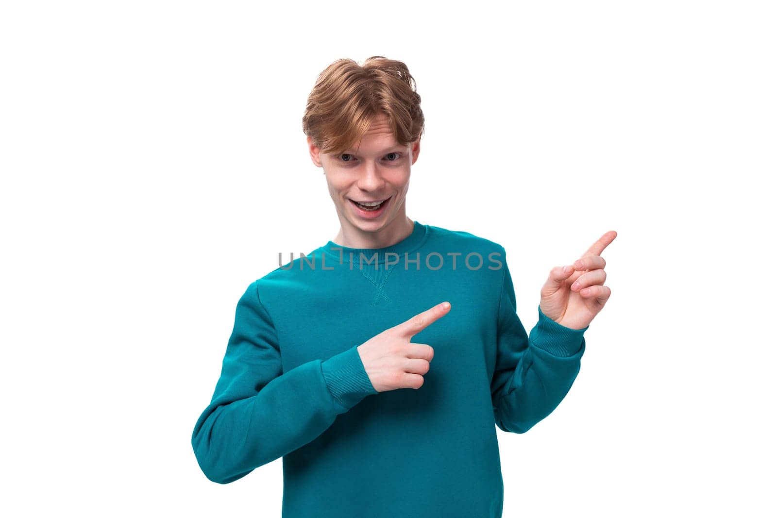 young handsome red-haired man with a blue sweater points his finger at the advertising space by TRMK