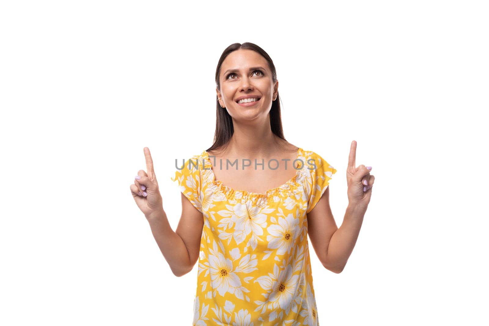 European brunette with flowing hair in a yellow t-shirt smiles with her teeth wide open.