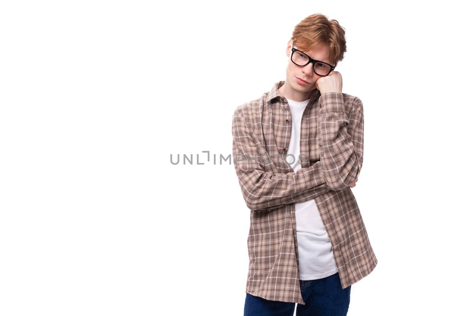 handsome red-haired caucasian student guy in glasses dressed in a plaid shirt is upset on a white background with copy space by TRMK