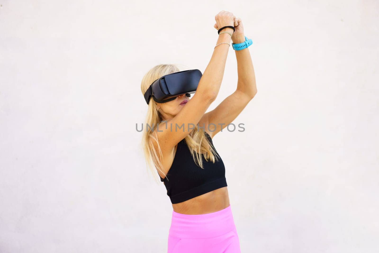 Sportswoman in VR headset raising hands while playing videogame by javiindy