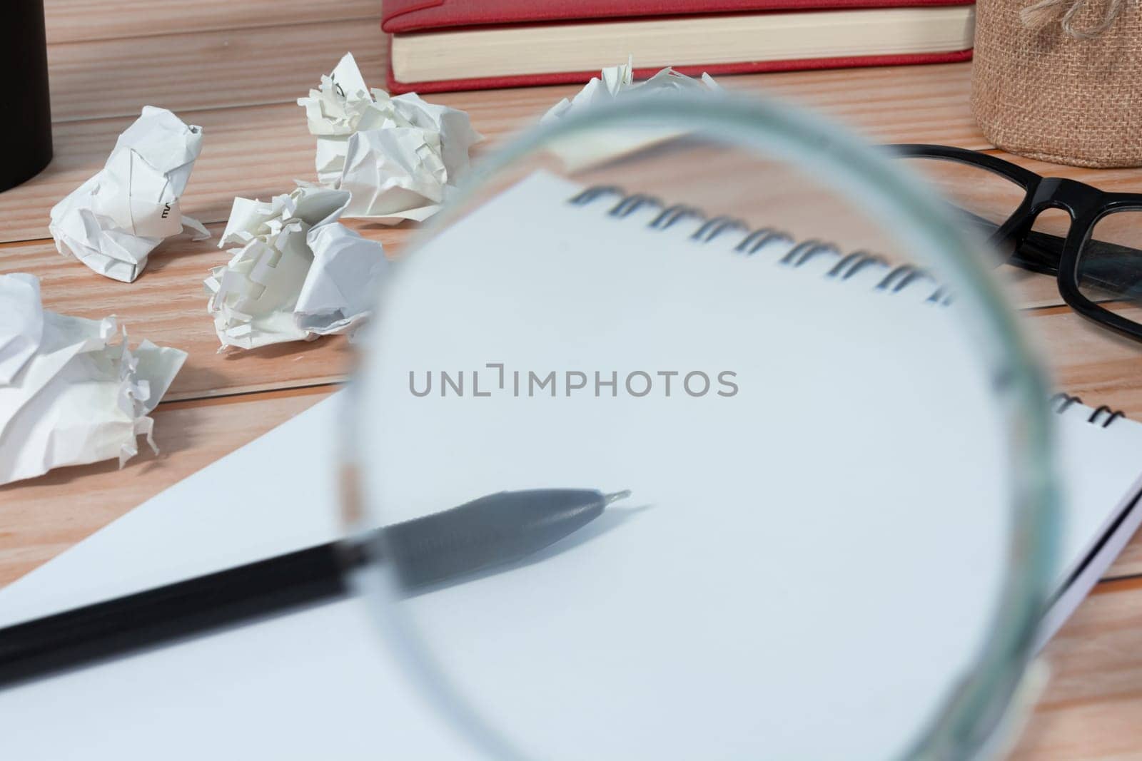 Magnifying glass on notepad and trash paper background on office desk. Business concept.