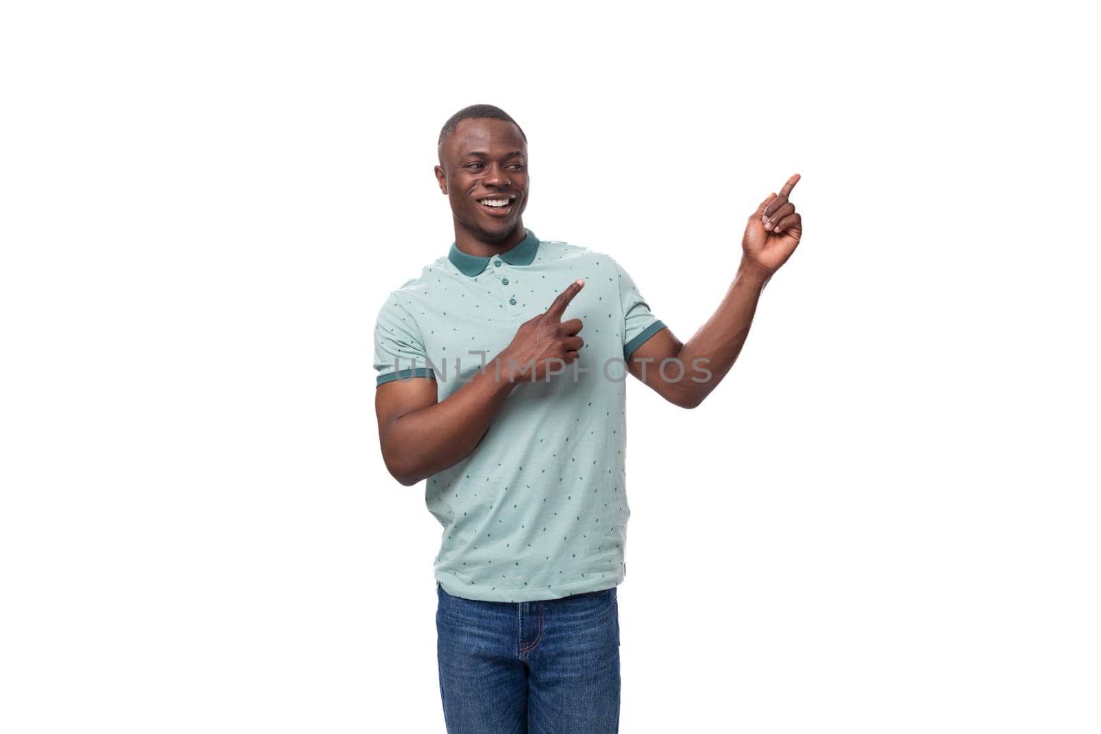 young african man dressed casually pointing with his hand to the side at an advertisement while standing on a white background with copy space by TRMK