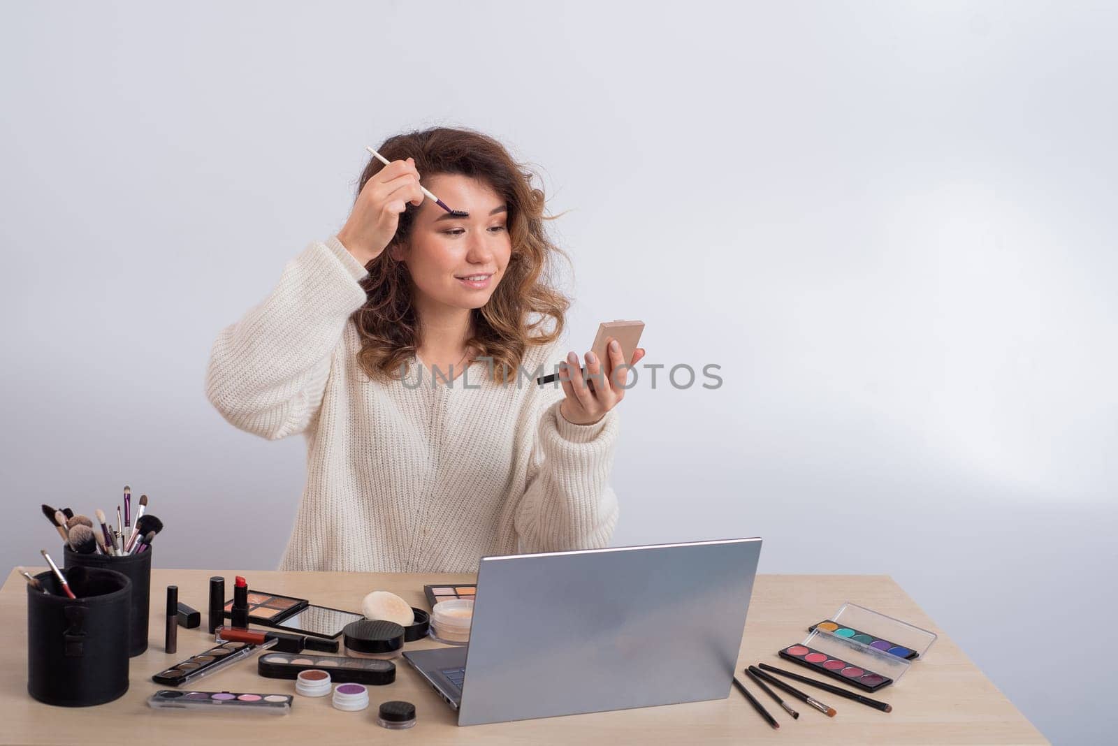 Young caucasian woman records video of online makeup training on a smartphone. Video blogger girl applies eye shadow by mrwed54