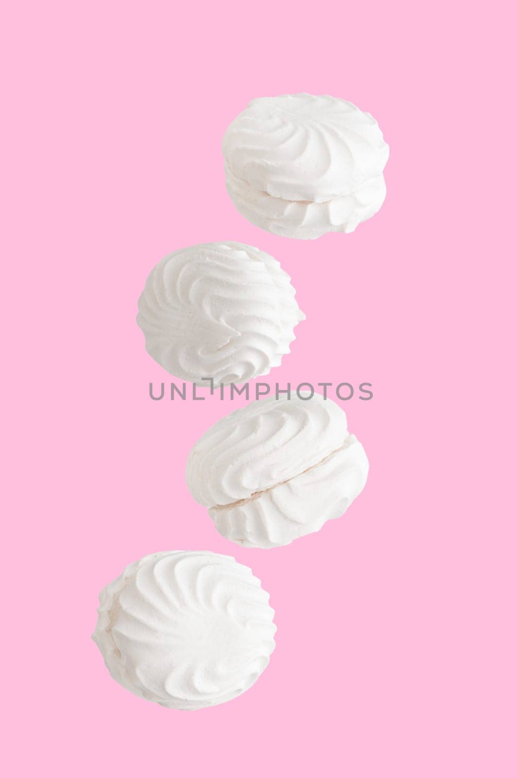 Soaring white zephyr marshmallow on pink background, sweet food levitation