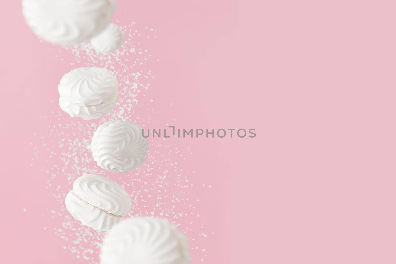 Soaring white zephyr marshmallow on pink background with sugar powder, levitation banner with copy space