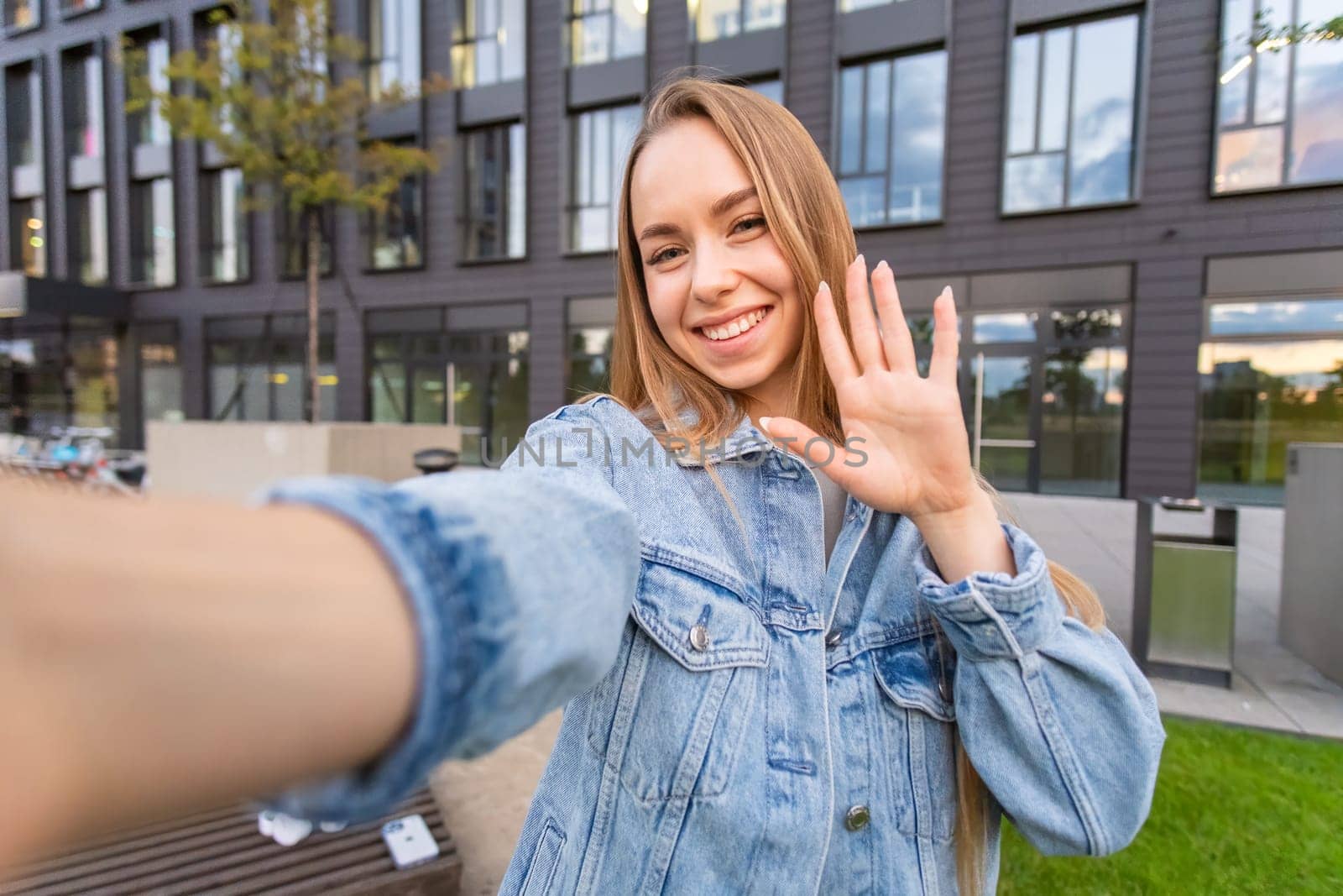 Attractive young female tourist with long blond hair taking a selfie in the street.