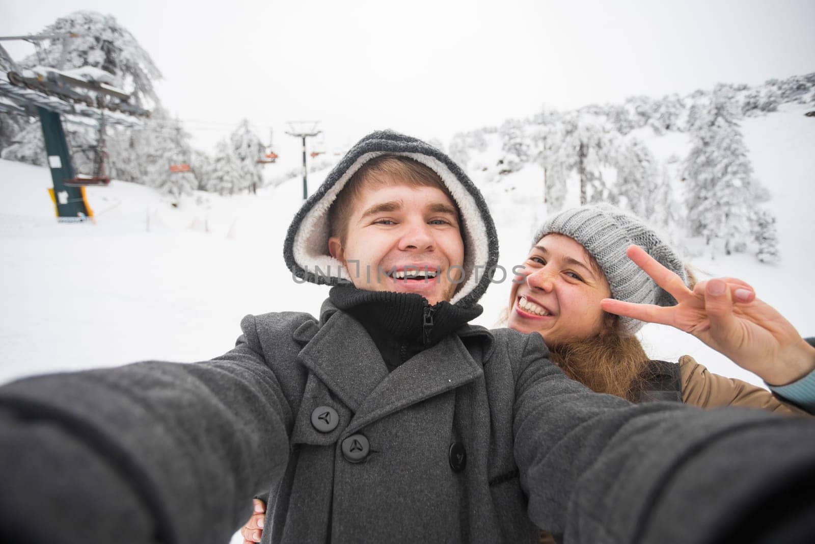 Young man and woman taking a selfie in winter using smart phone