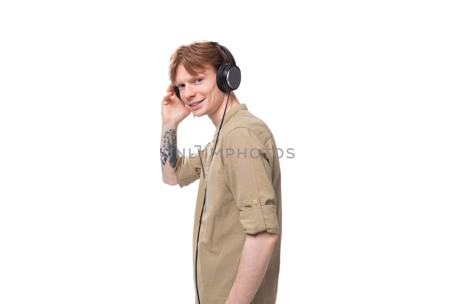 young cute caucasian guy with red hair listens to favorite playlist in headphones.