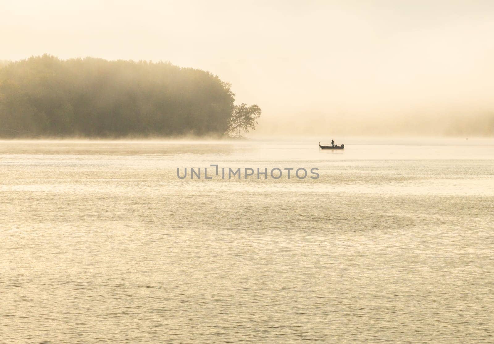 Fisherman in water of Upper Mississippi on calm misty morning near Dubuque in Iowa