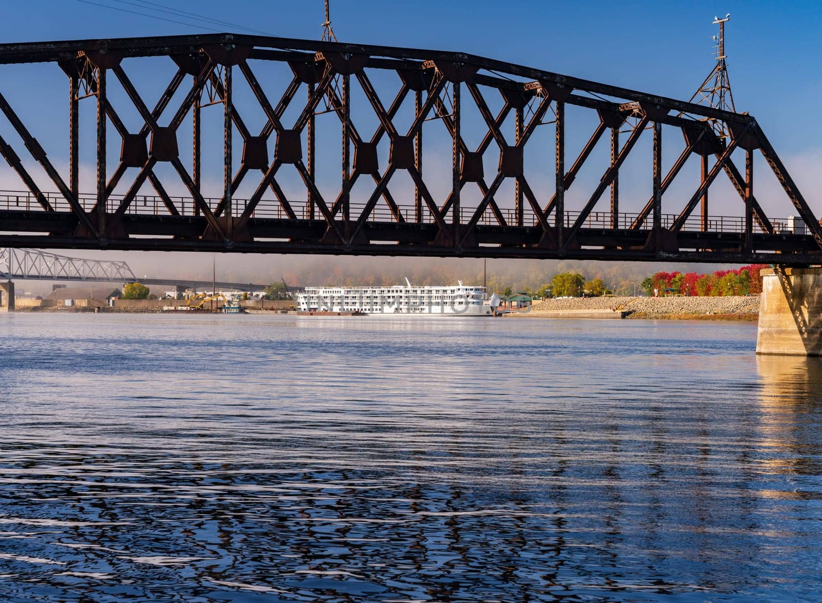 Dubuque Railroad bridge across Upper Mississippi on calm misty morning with docked river cruise boat