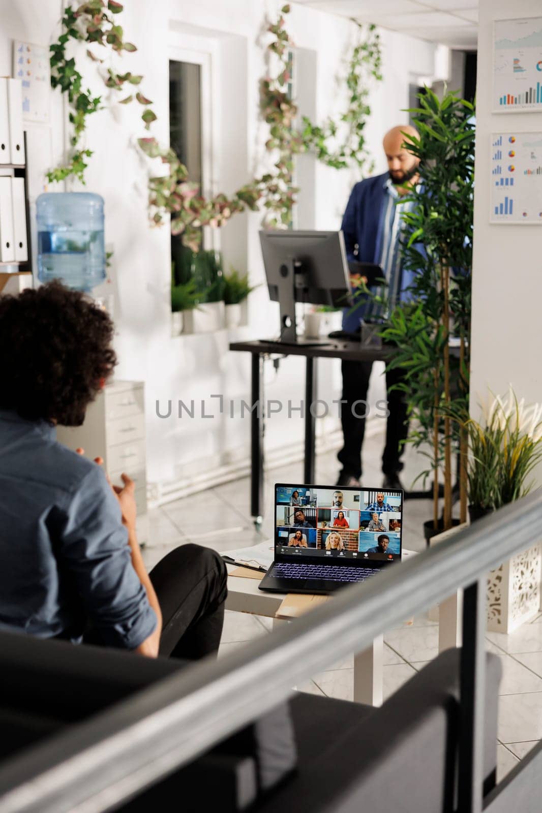 Executive manager discussing strategy with remote workers team on laptop screen while sitting in business office. Businessman and colleagues having virtual conference on portable computer