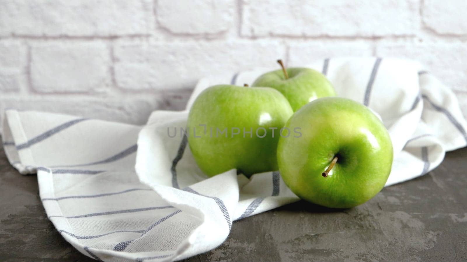 Ripe green apples and napkin on kitchen counter top.