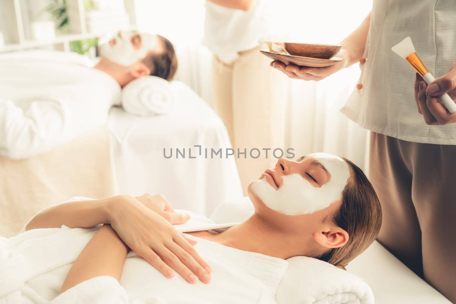 Serene ambiance of spa salon, couple indulges in rejuvenating with luxurious face cream massage with modern daylight. Facial skin treatment and beauty care concept. Quiescent