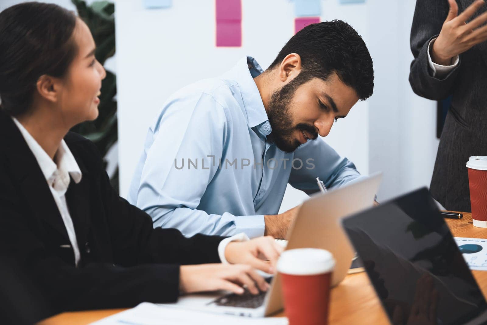 Professional Asian employee work together as team in corporate office, discussing business plans and data to achieve success on desk with laptop. Modern office worker teamwork concept. Concord