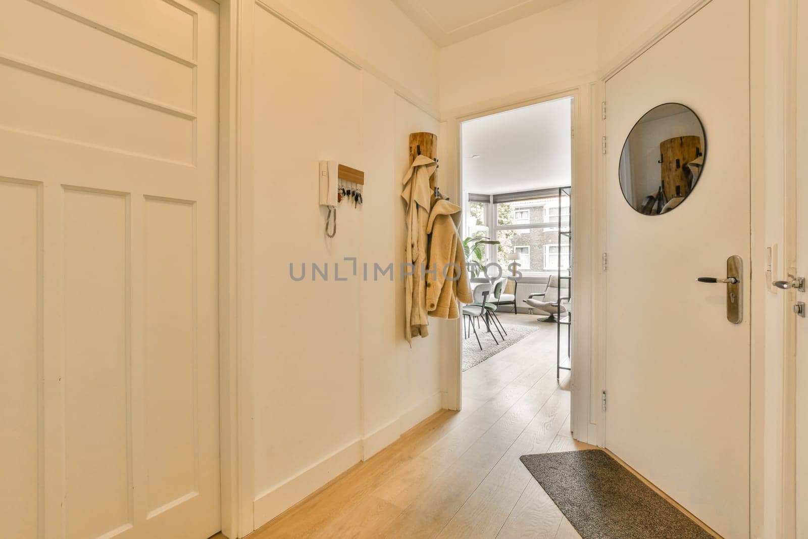 a hallway with white walls and wood flooring the door is open to reveal an entry way that leads into a living room