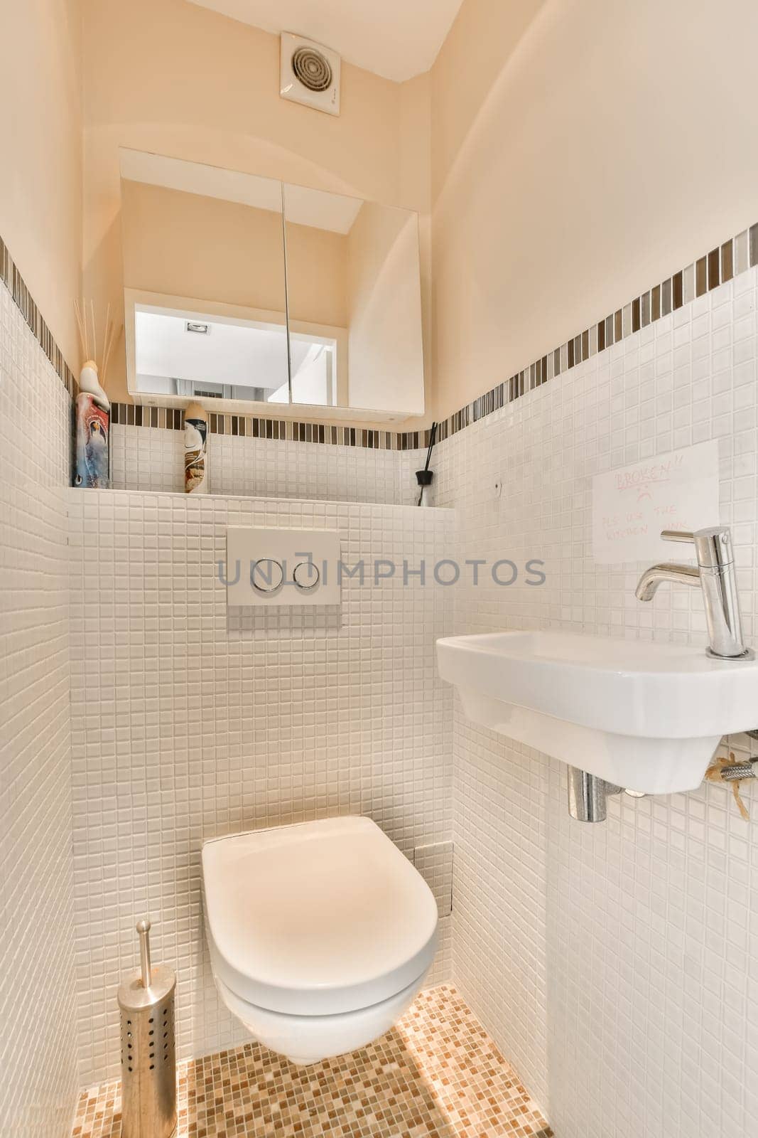 a white toilet in a small bathroom with tiled floor and wall tiles on the walls there is a mirror above it