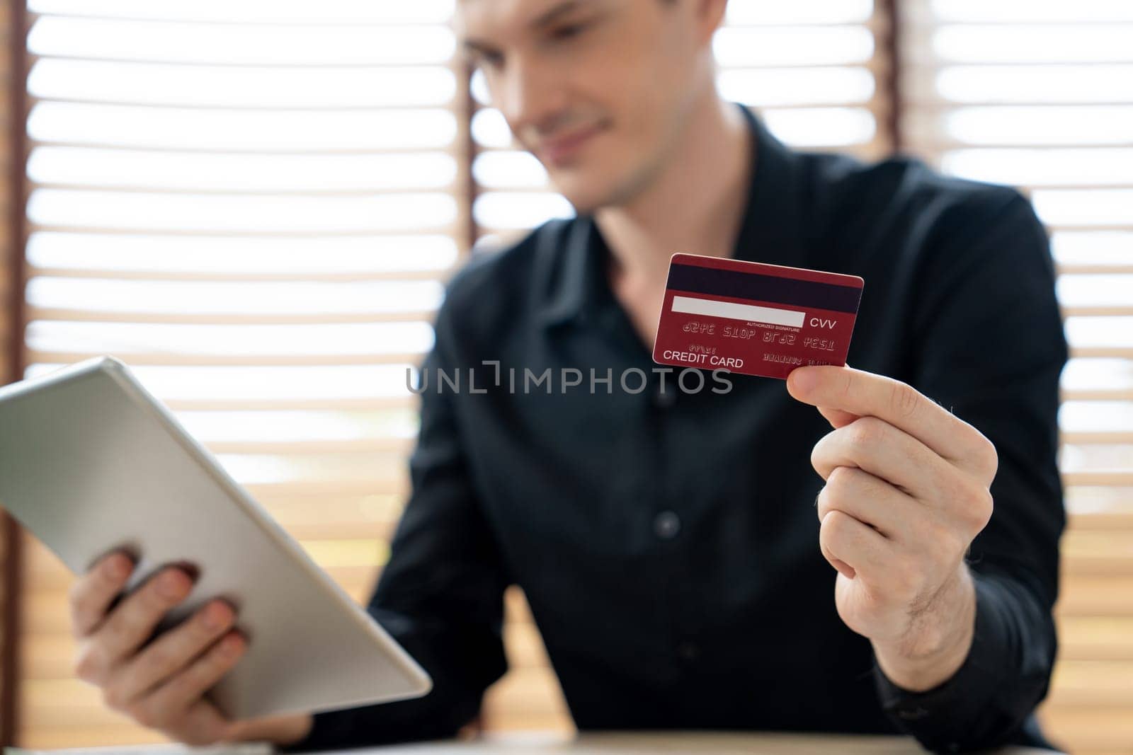 Young man using tablet with credit card for internet banking. Unveiling by biancoblue