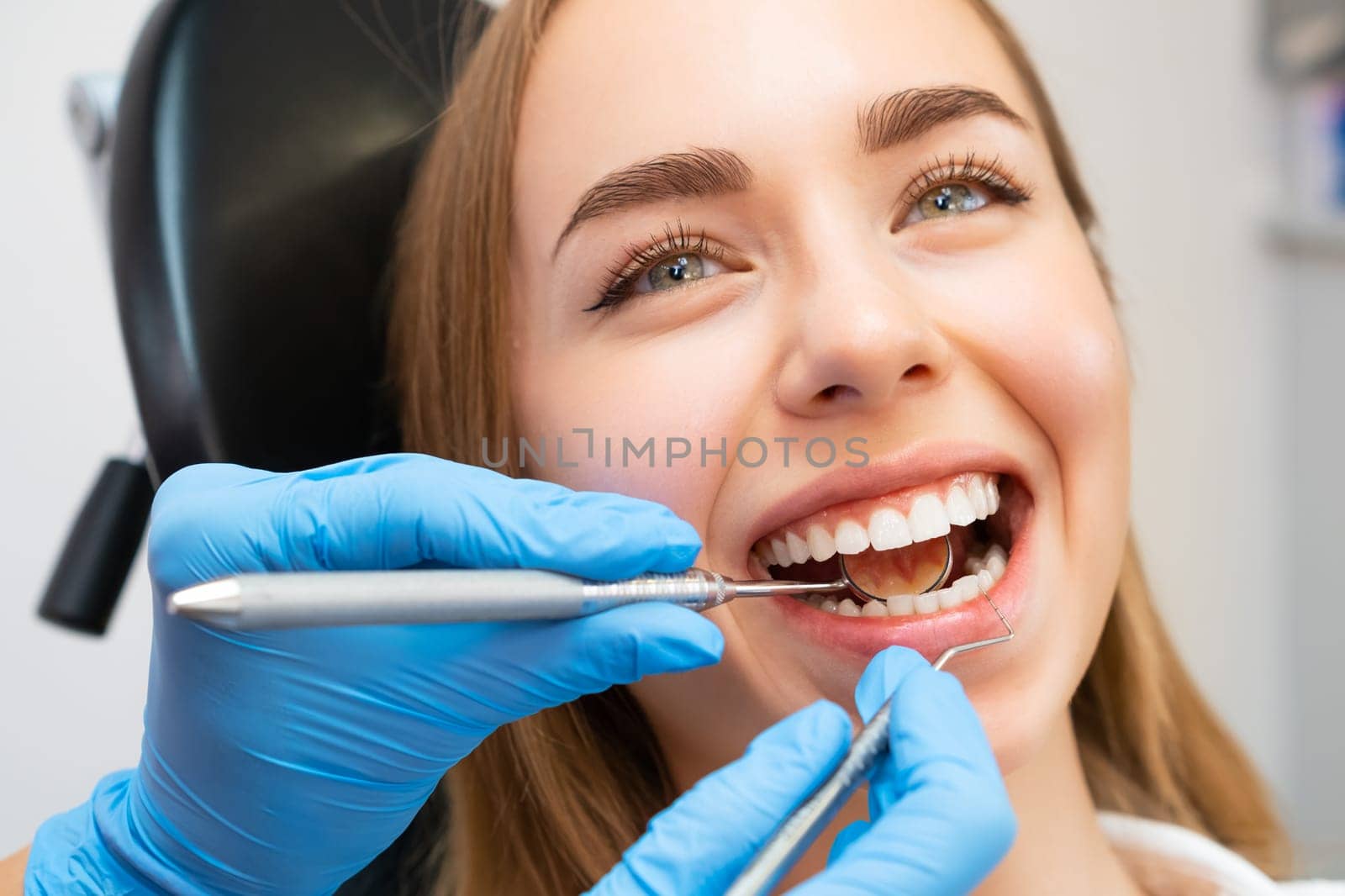 The dentist uses a small mirror and dental probe to inspect the patients teeth and gums. by vladimka
