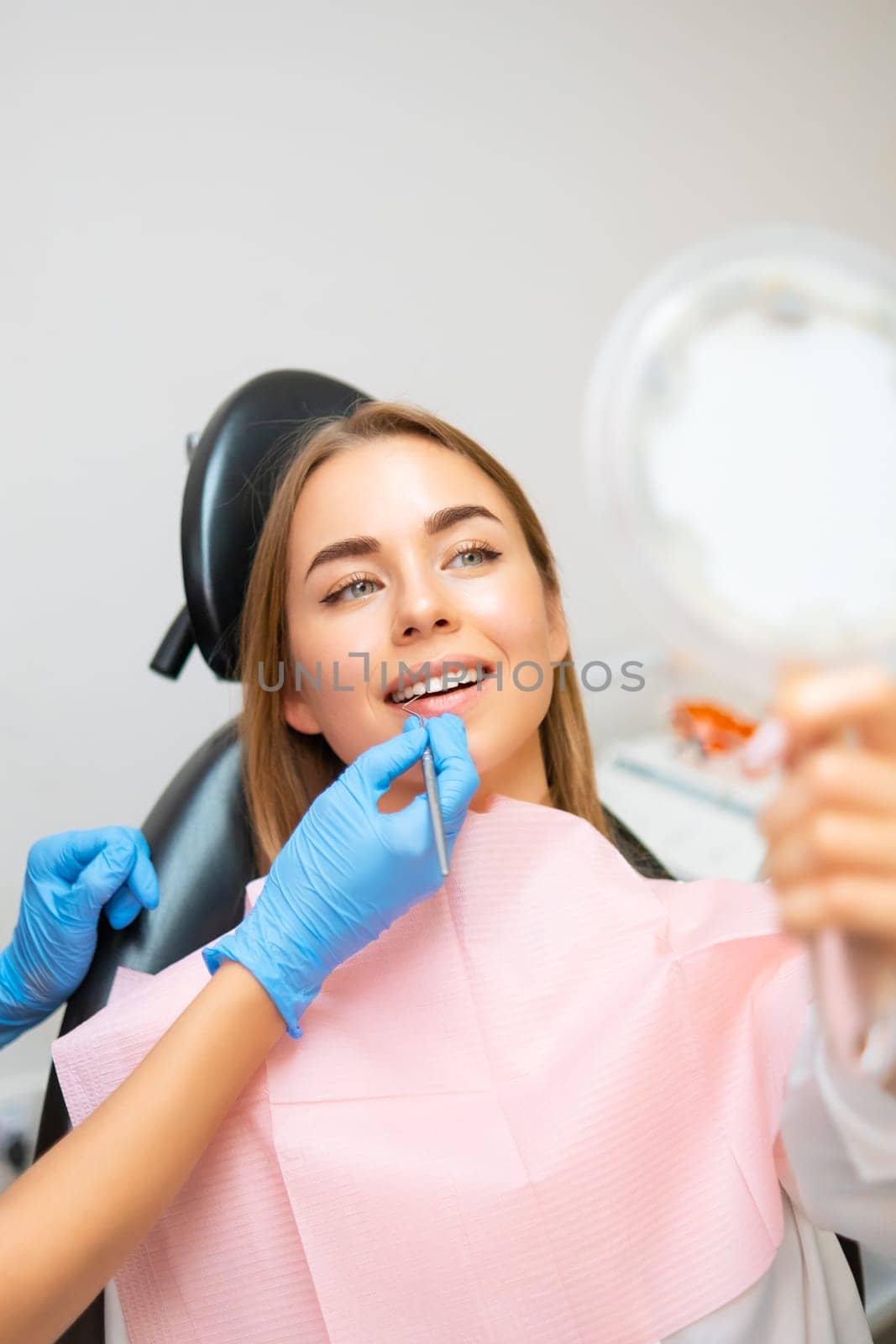 Woman examines her radiant smile in the mirror after teeth whitening by vladimka